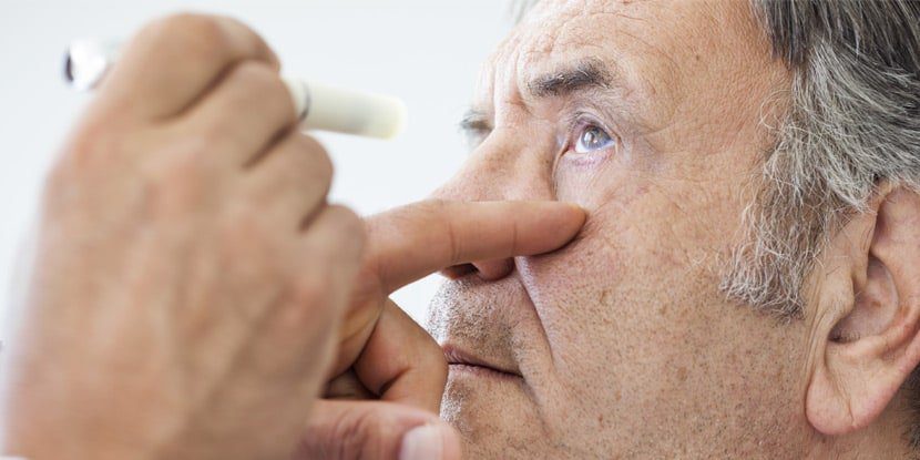 Penlight eye exam of older man